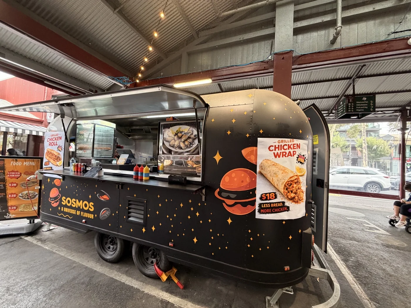 The black SOSMOS food truck under the historic roof at Queen Victoria Market